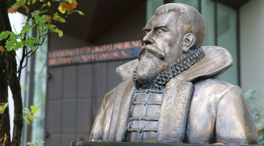 Büste aus Messing von Philipp Apian, berühmter bayerischer Kartograf des 16. Jahrhunderts. Die Büste zeigt ihn hier mit Vollbart. Er trägt ein geknöpftes Wams, darüber einen offenen Mantel mit Pelzkragen. Den Hals umschließt die für diese Zeit typische Halskrause. 